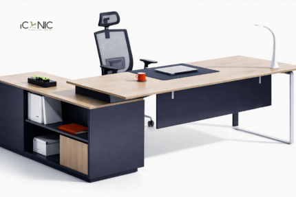 L-shaped executive desk with light oak wood top, charcoal grey base, and C-shaped metal leg.